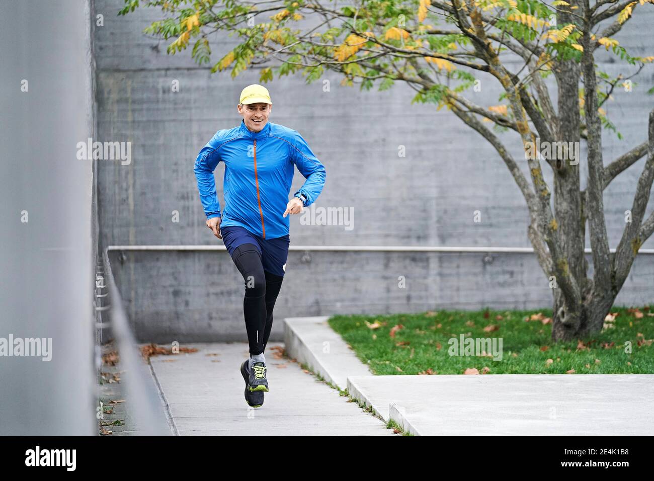 Smiling mature man running with dedication on footpath Stock Photo