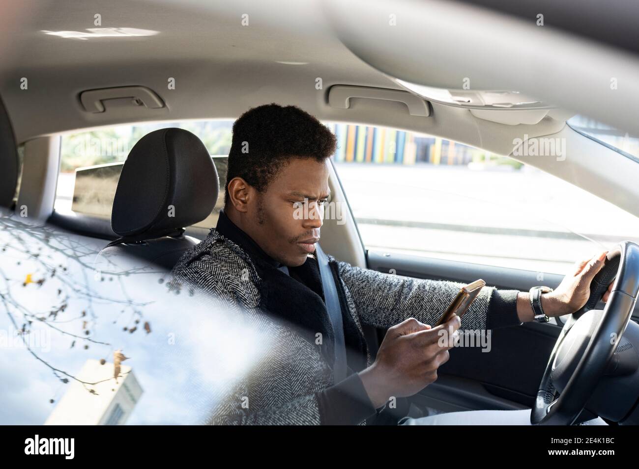 Young man driving car and using smartphone Stock Photo
