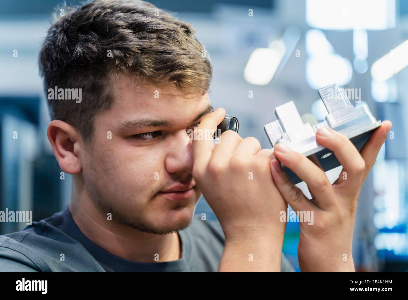 Young engineer examining small microscope while working at industry ...