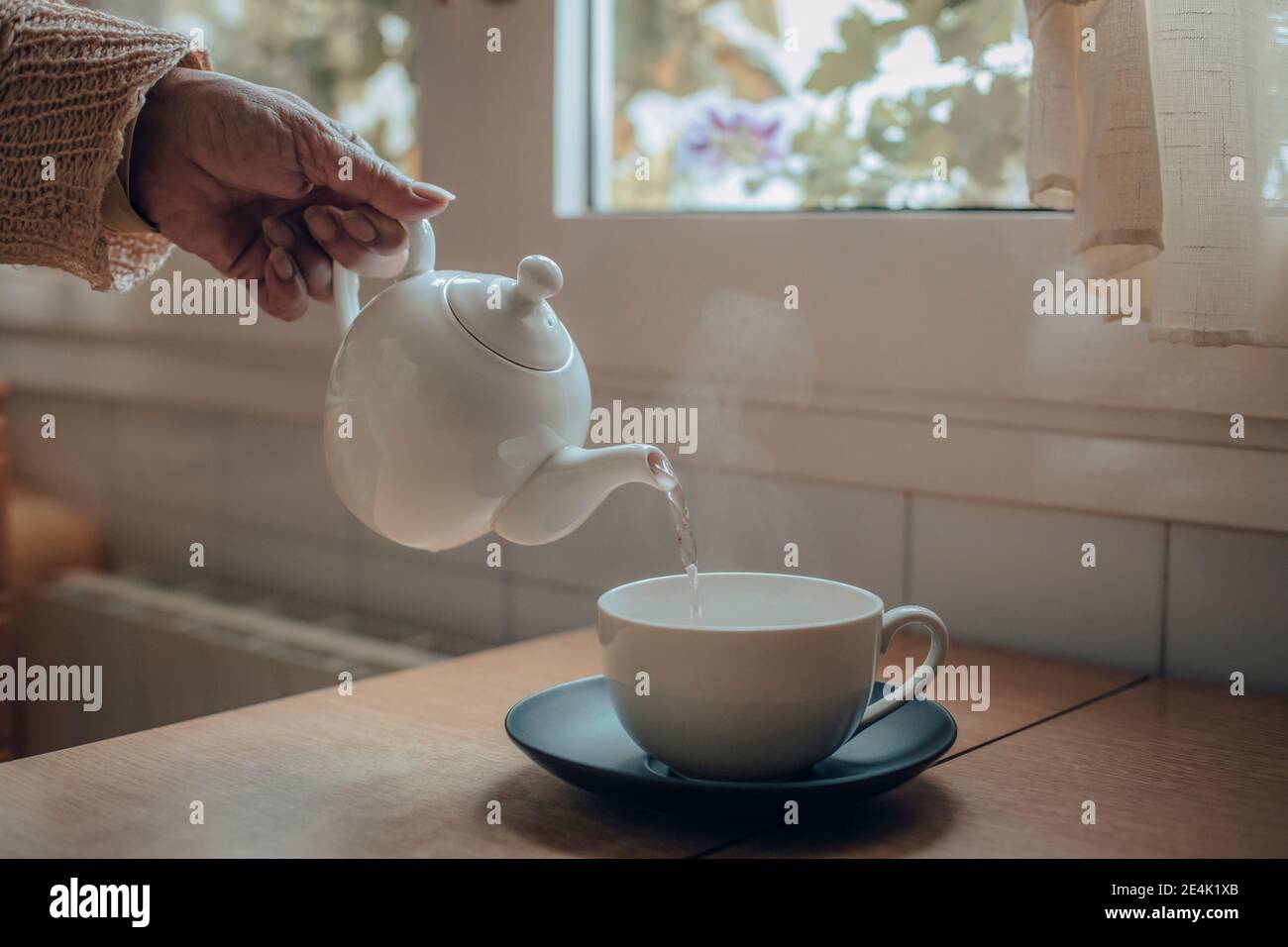 Hand holding tea kettle hi-res stock photography and images - Alamy