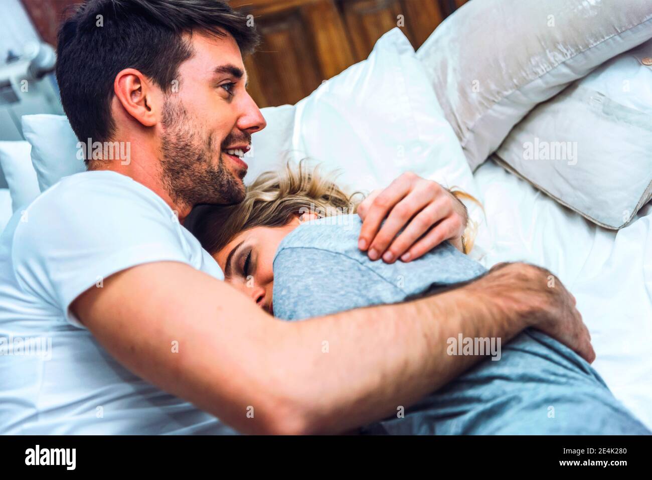 Happy affectionate young couple cuddling in bed at home Stock Photo