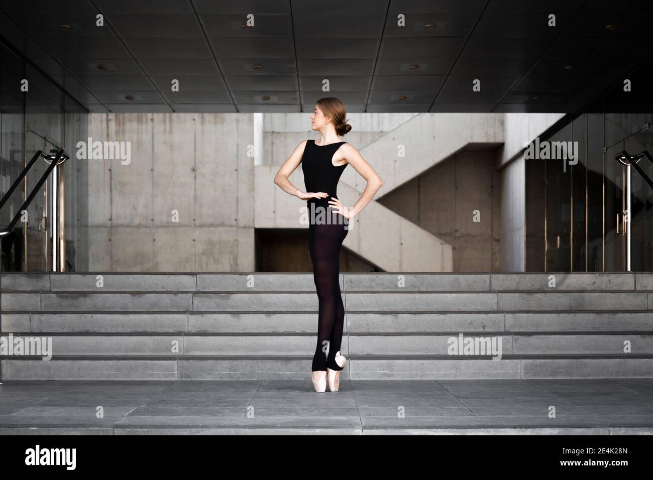 Ballerina in black leotard in modern concrete building Stock Photo