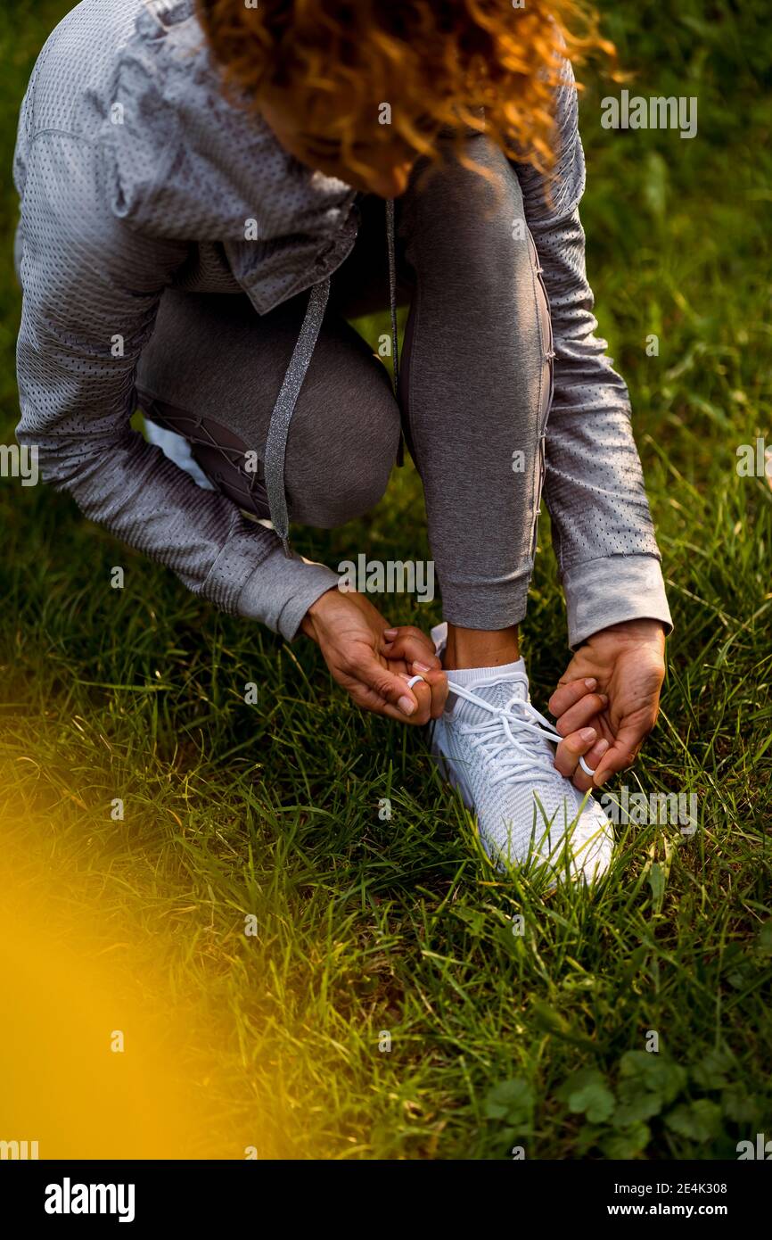Female athlete tying shoelace while crouching at park Stock Photo