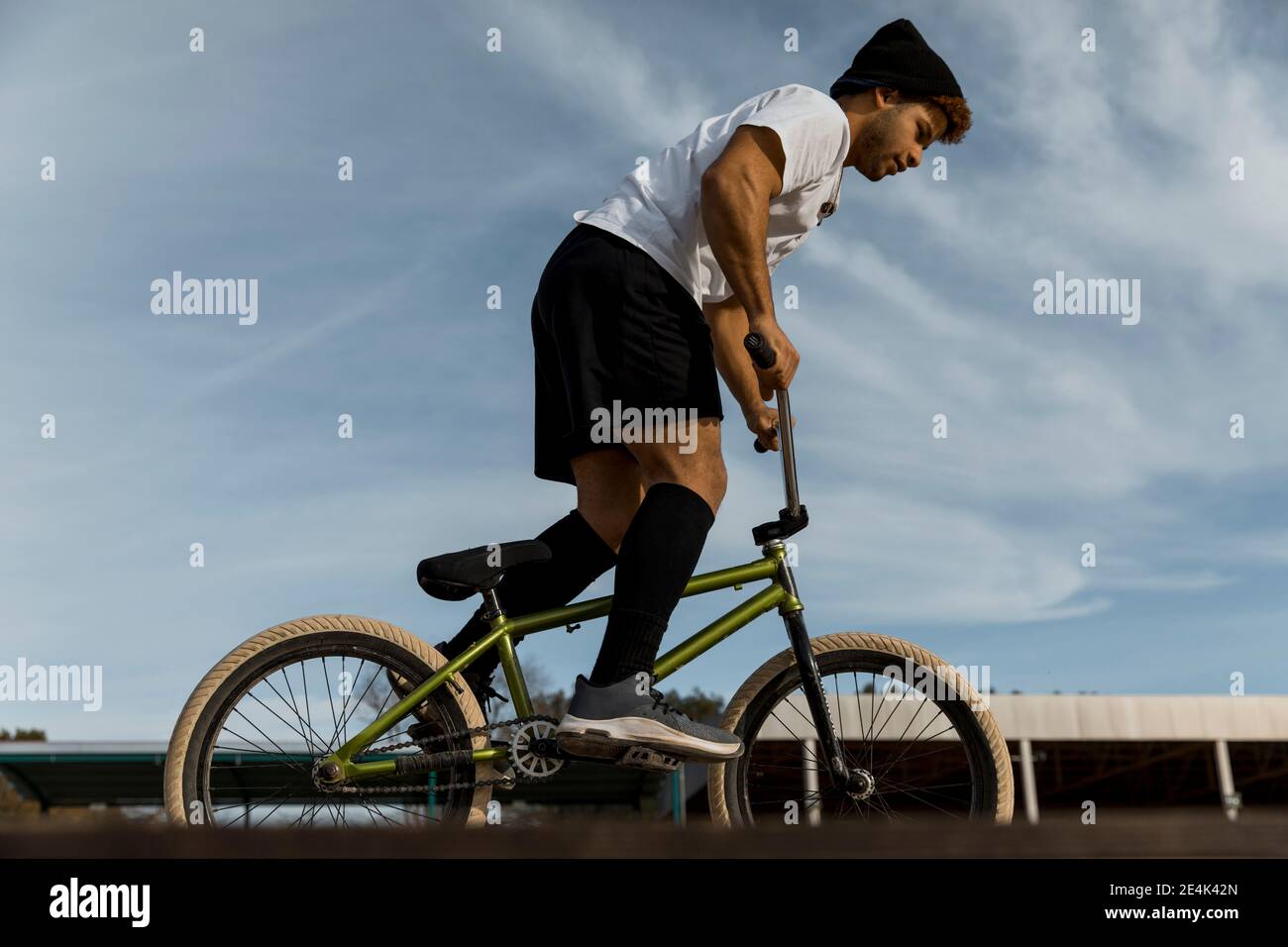 Young man with cycling against sky on sunny day Stock Photo