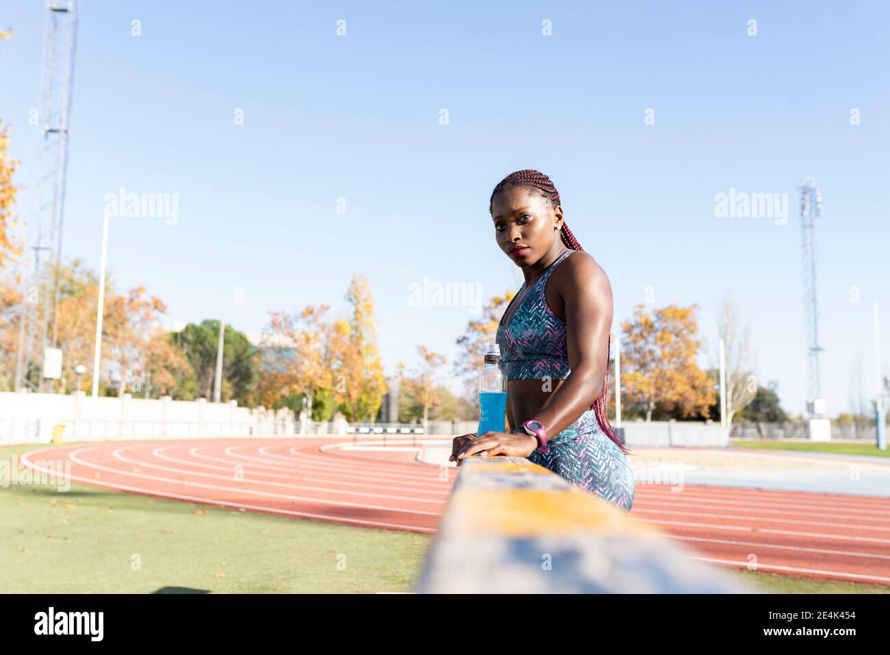 Sportswoman with energy drink standing by balance beam on sunny day Stock Photo