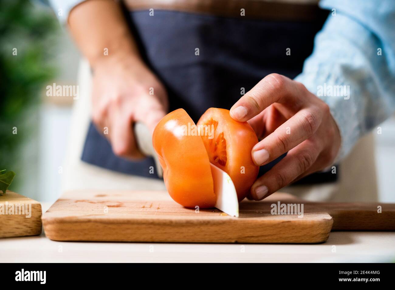 Hands of woman slicing tomato on cutting board Stock Photo