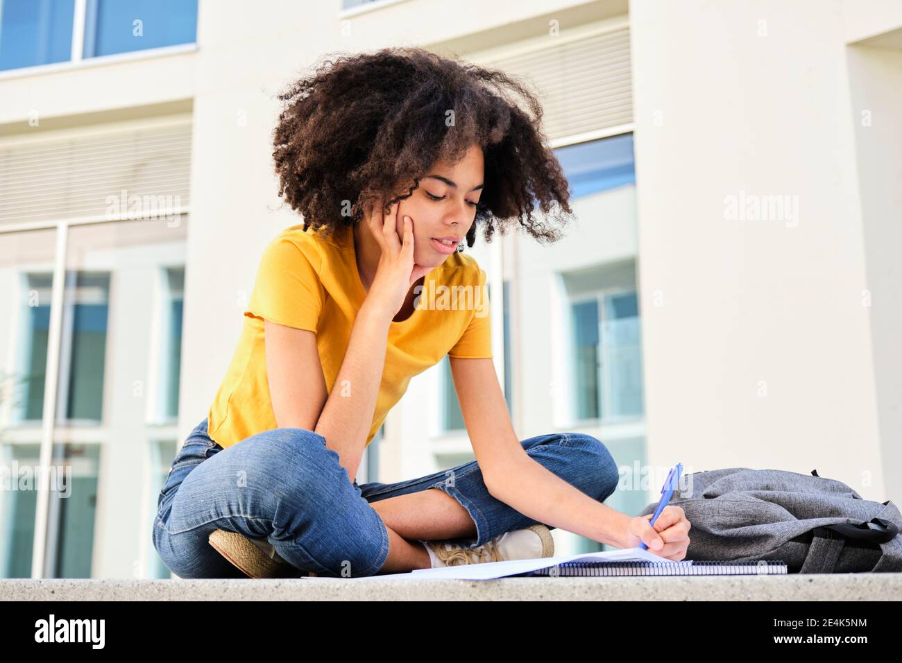 Curly hair student studying while sitting at university campus Stock ...