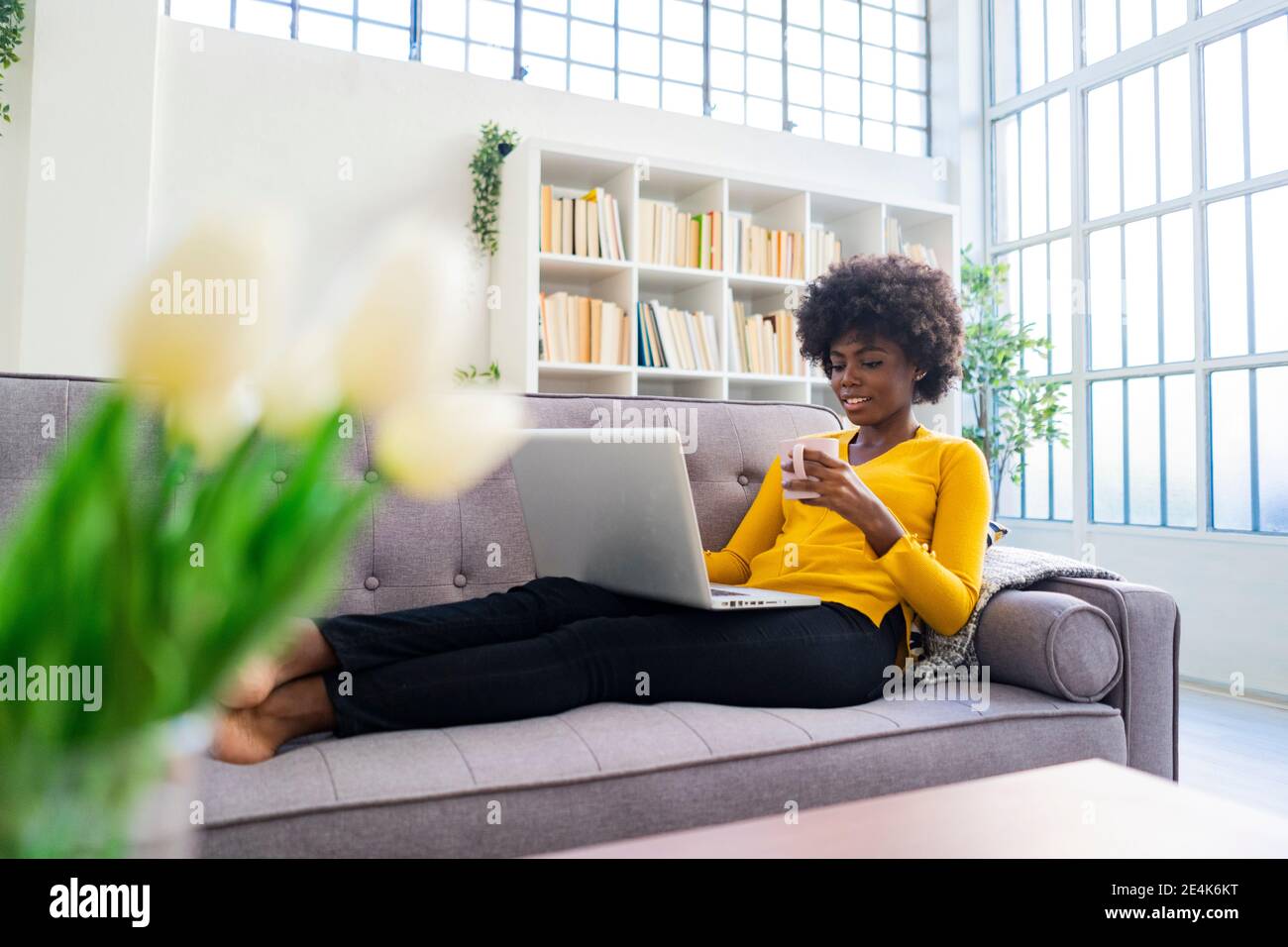 Woman drinking coffee while working on laptop at home Stock Photo