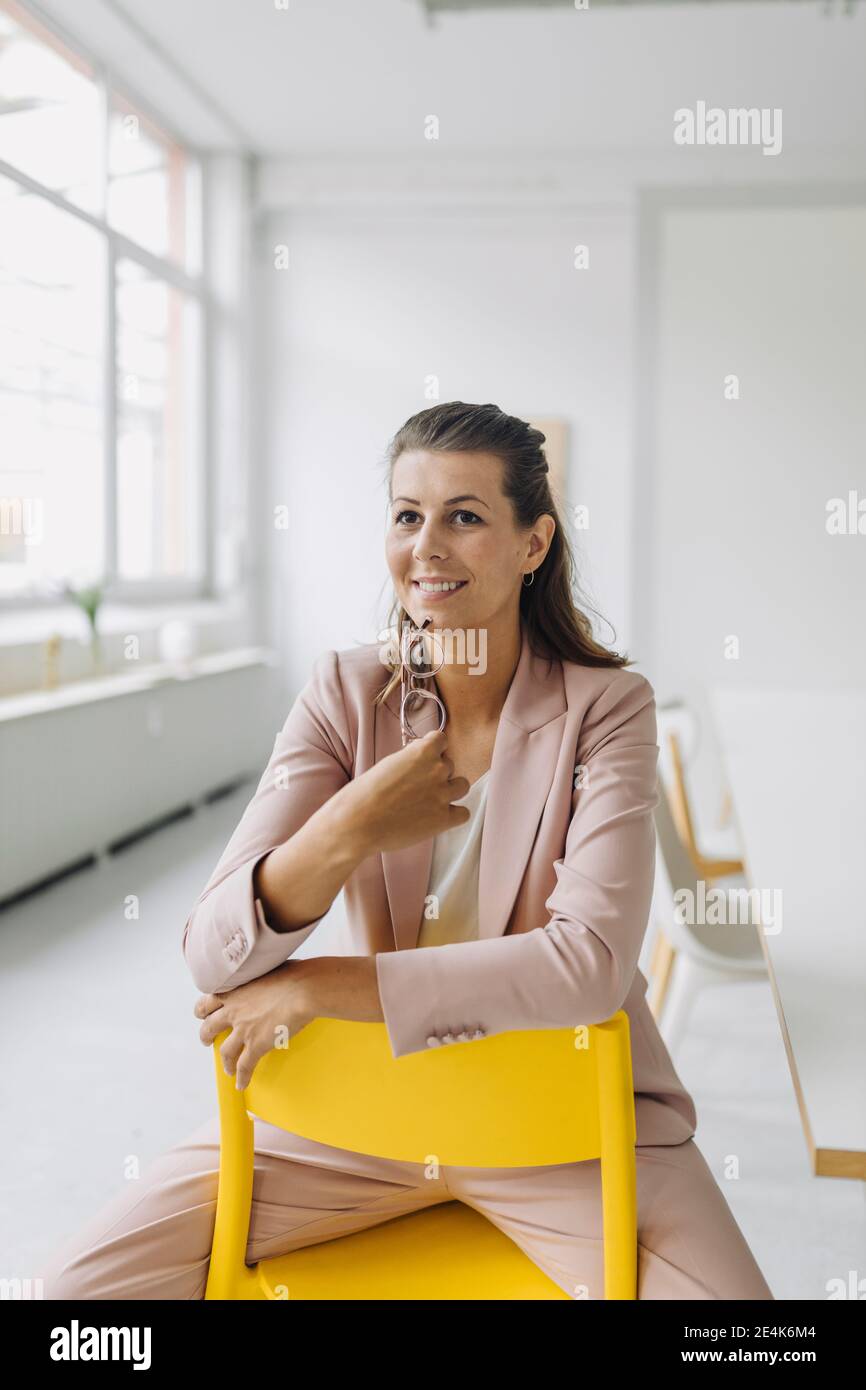 Portrait of smiling businesswoman sitting on chair in empty office
