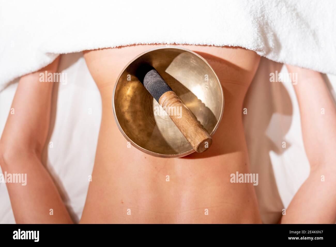Mallet in rin gong on female customer's back lying on massage table at health spa Stock Photo