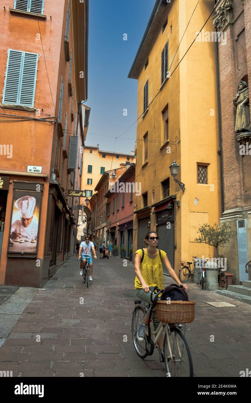 Couple cycling through the historic narrow streets of Bologna, Northern Italy, Europe. Stock Photo