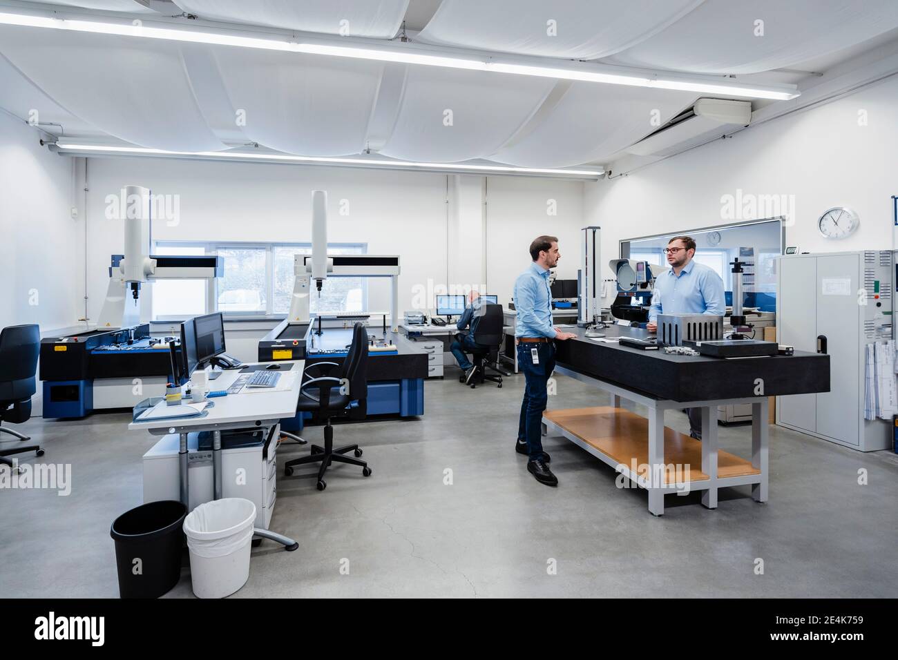 Engineers talking while standing in measuring room at office Stock Photo