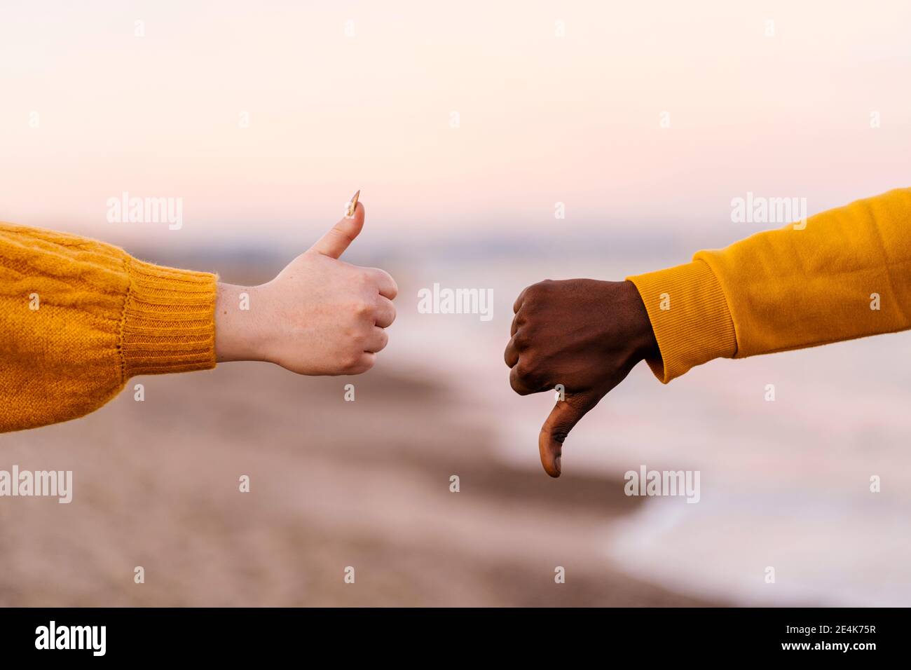 Woman and man showing thumps up and down gesture at beach Stock Photo