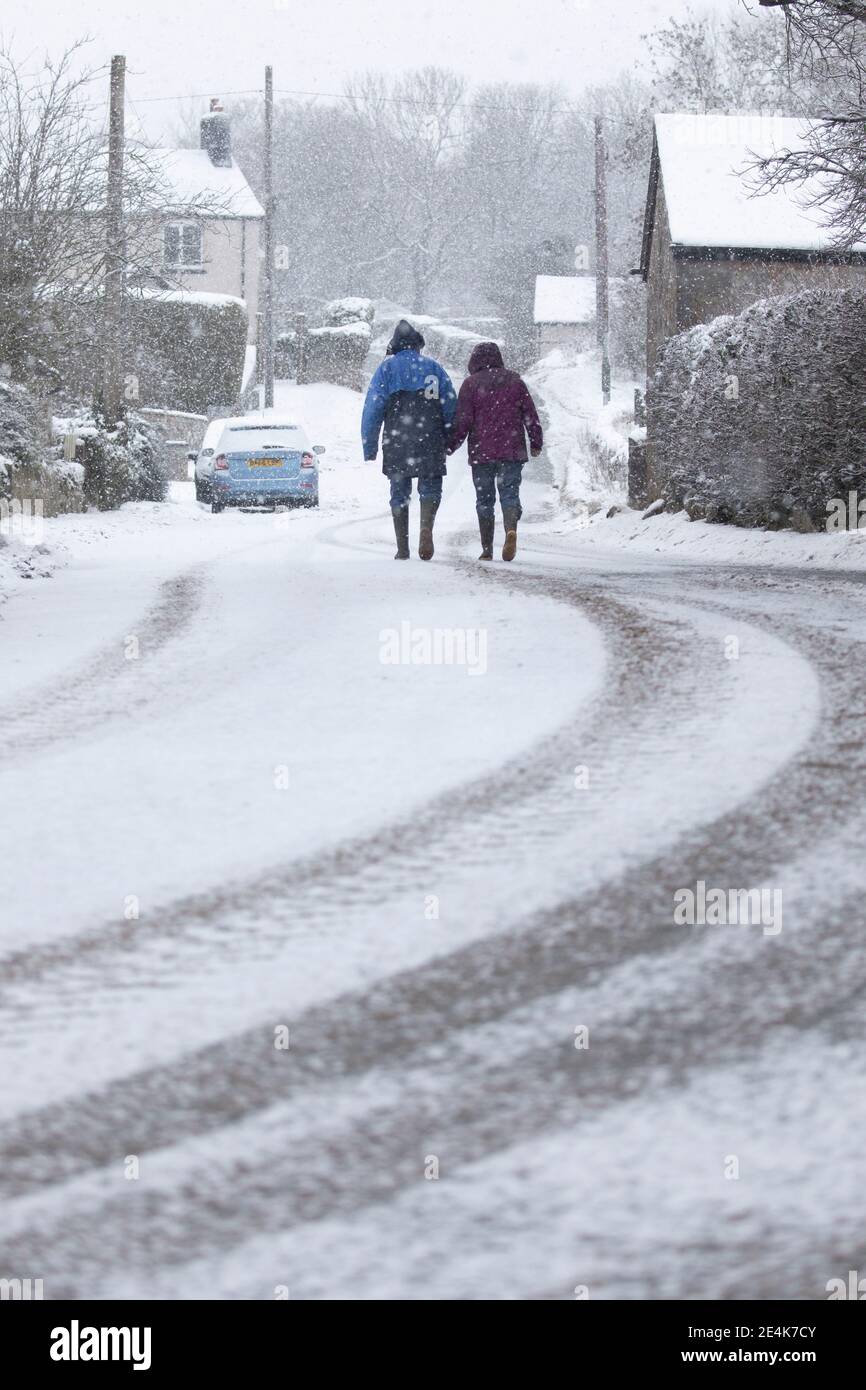 Flintshire, North Wales, UK Wednesday 24th January 2021, UK Weather:  Heavy snowfall in North Wales with a Met Office weather warning in place snow as a weather front tracks eastward across the country. A couple in the village of Lixwm braving the heavy snowfall which is set for the day in the area of Flintshire  © DGDImages/Alamy Live News Stock Photo