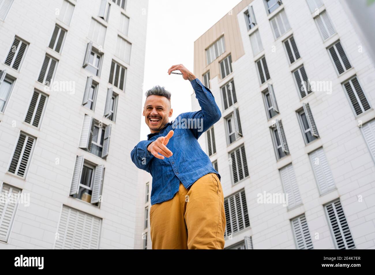 Cheerful man dancing against white buildings Stock Photo