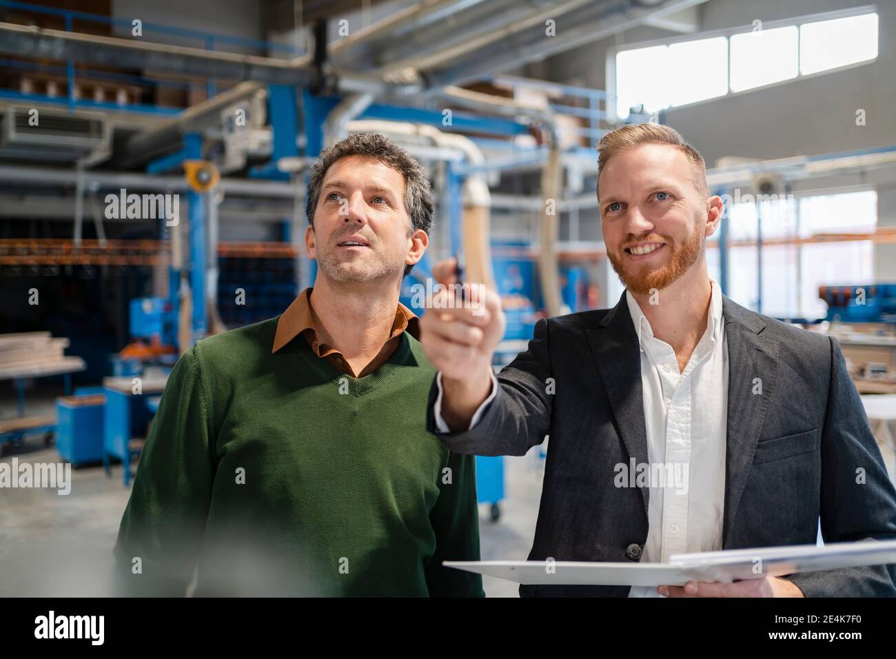 Two carpenters standing side by side and talking in production hall Stock Photo