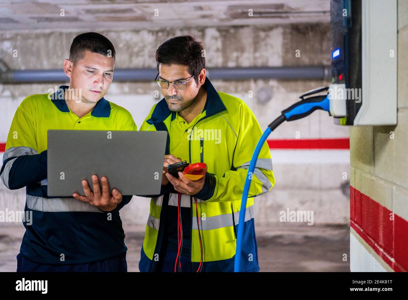 Professional male programmers discussing while working on laptop in auto repair shop Stock Photo