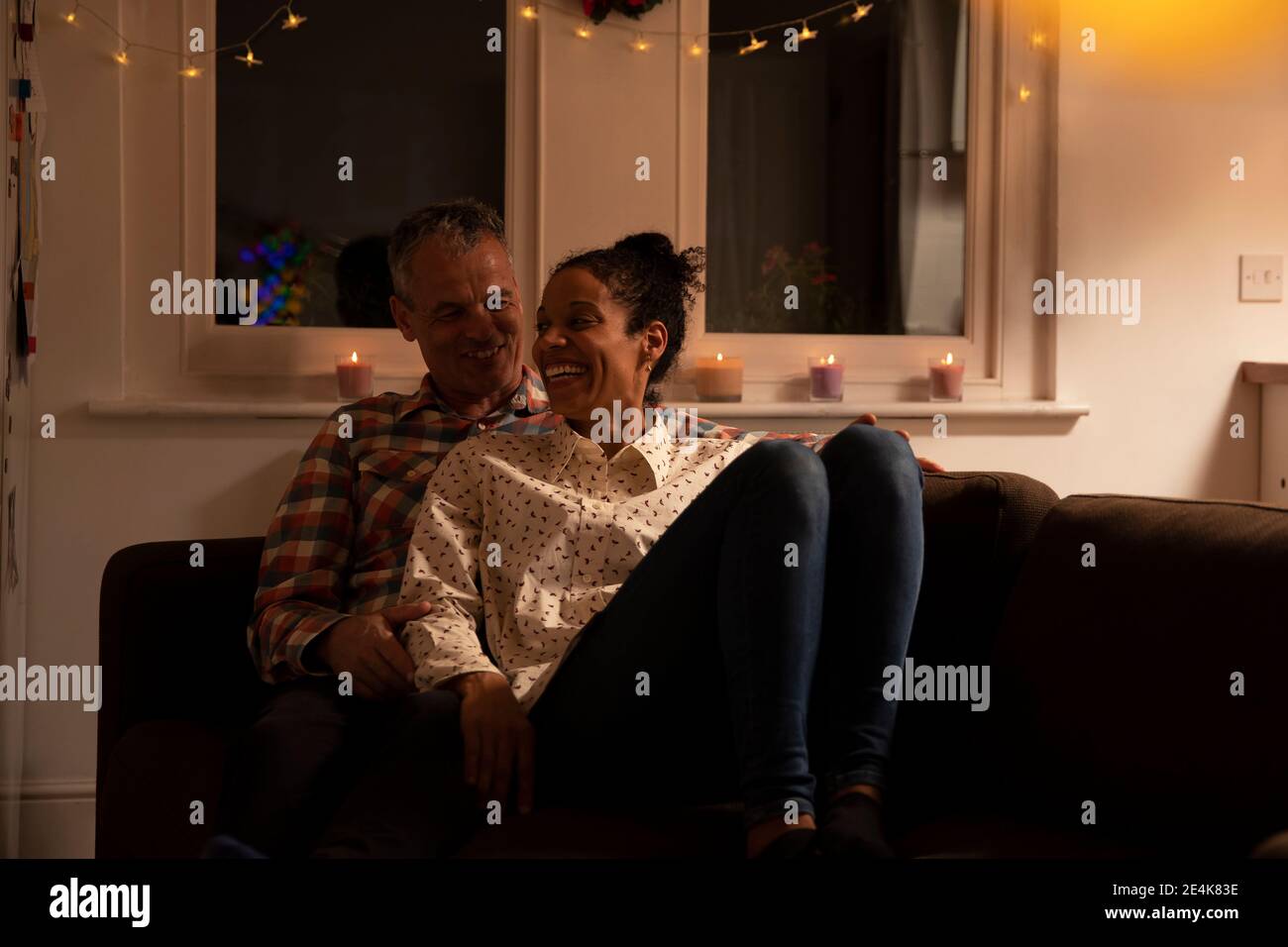 Smiling couple talking while relaxing on sofa at home Stock Photo