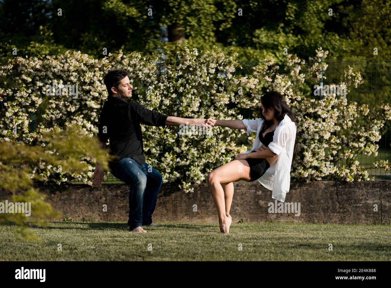 Heterosexual couple dancing while holding hand over grass in back yard Stock Photo