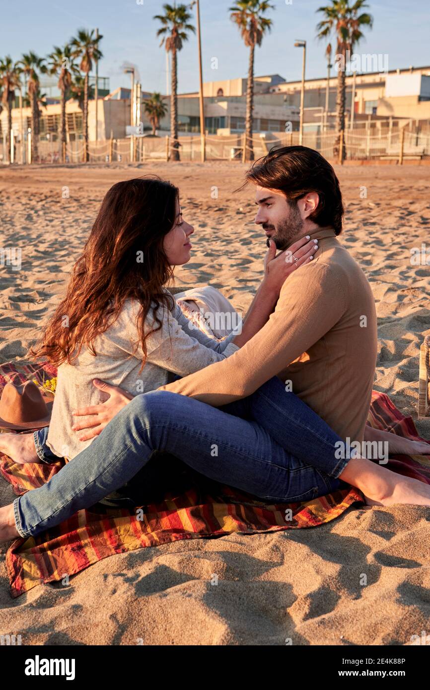 Young couple doing romance while sitting on beach Stock Photo