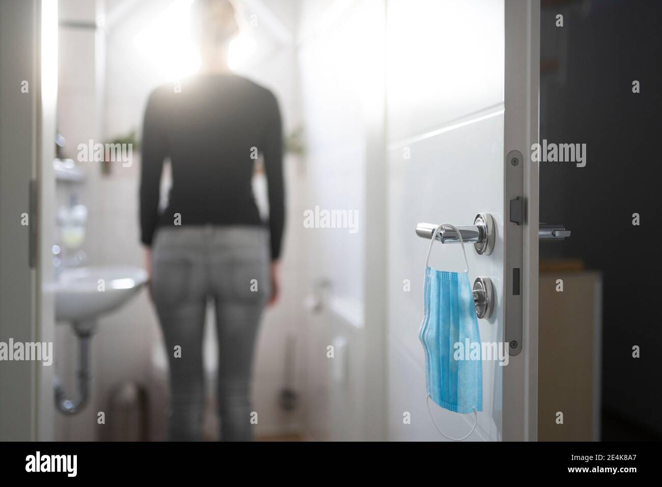 Mid adult woman standing in bathroom at home during COVID-19 Stock Photo