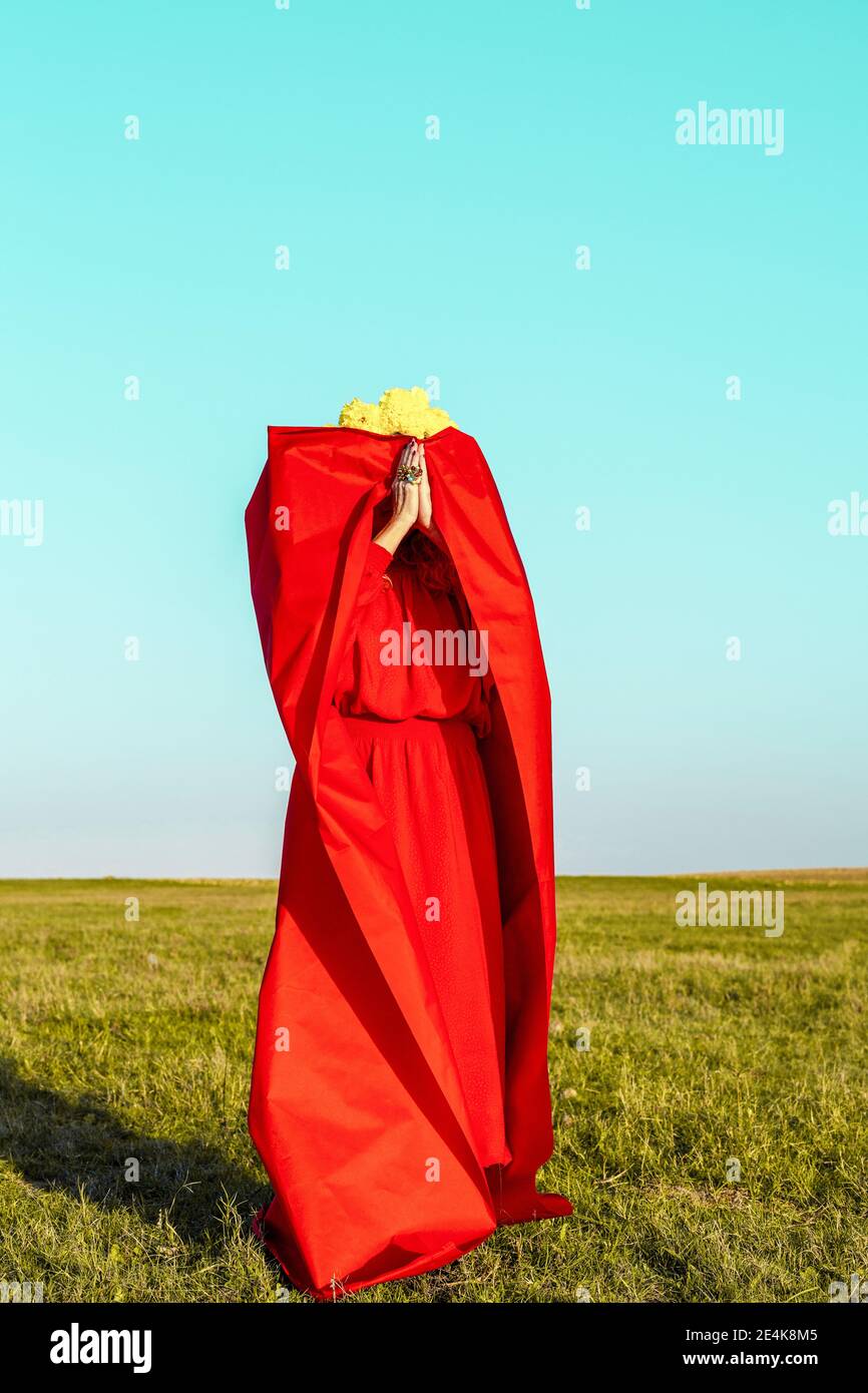 Senior woman covered in long dress while standing on grass during sunny day Stock Photo