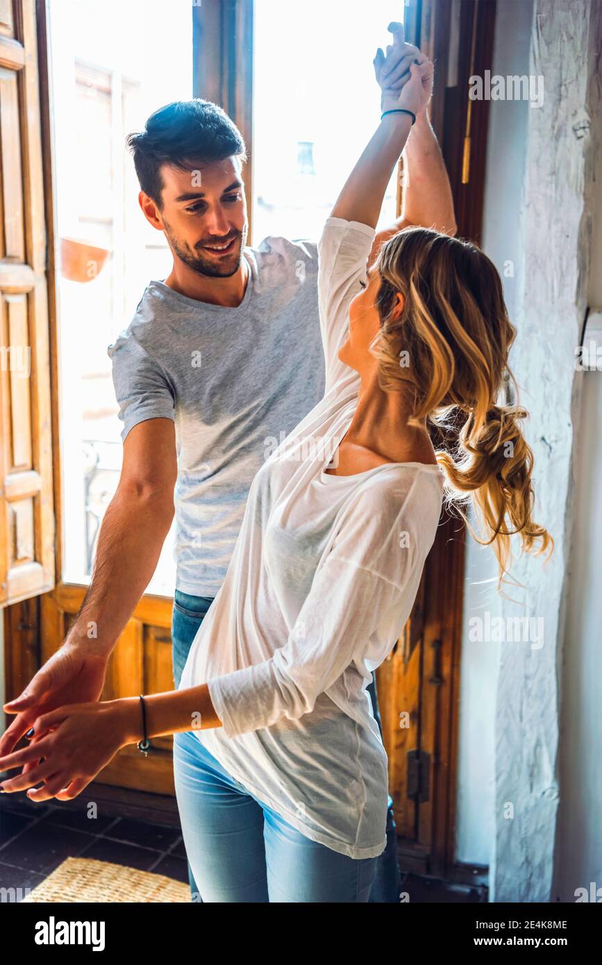 Young couple dancing at the window at home Stock Photo