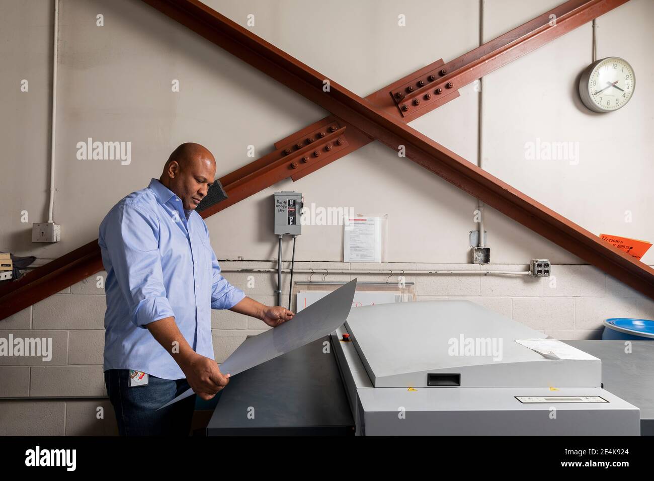 Smiling employee with arms crossed looking down while leaning on