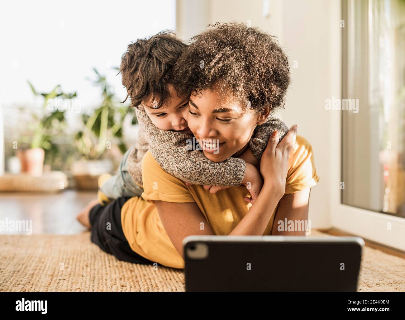 Smiling mother with son using digital tablet while lying at home Stock Photo
