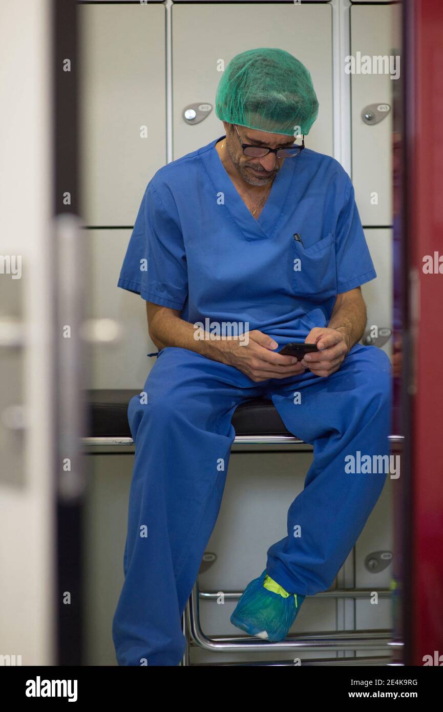Male doctors watching monitoring equipment while operating patient at hospital Stock Photo
