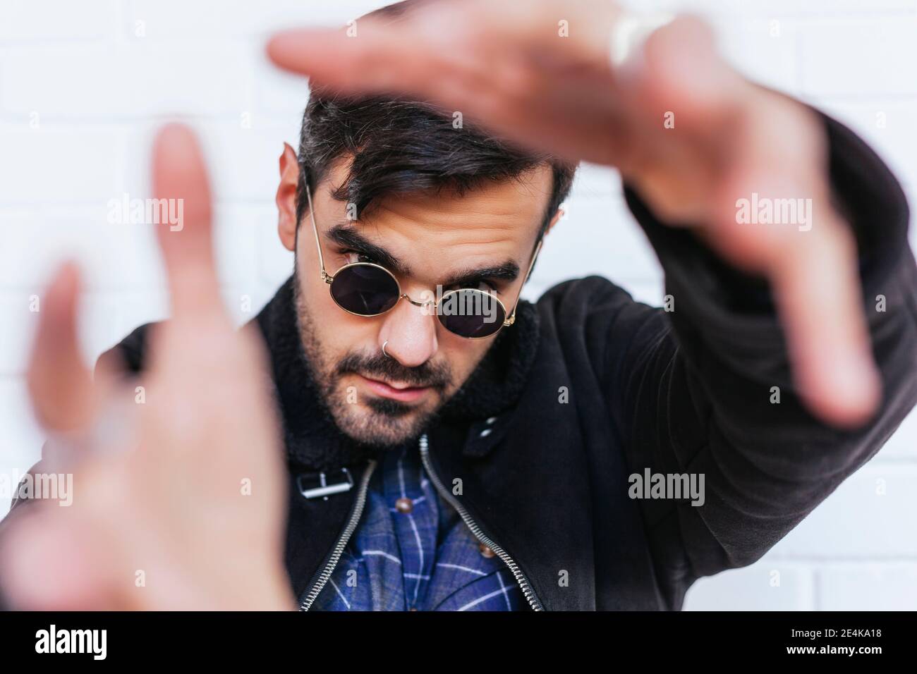 Fashionable young man wearing nose ring gesturing against white wall Stock Photo