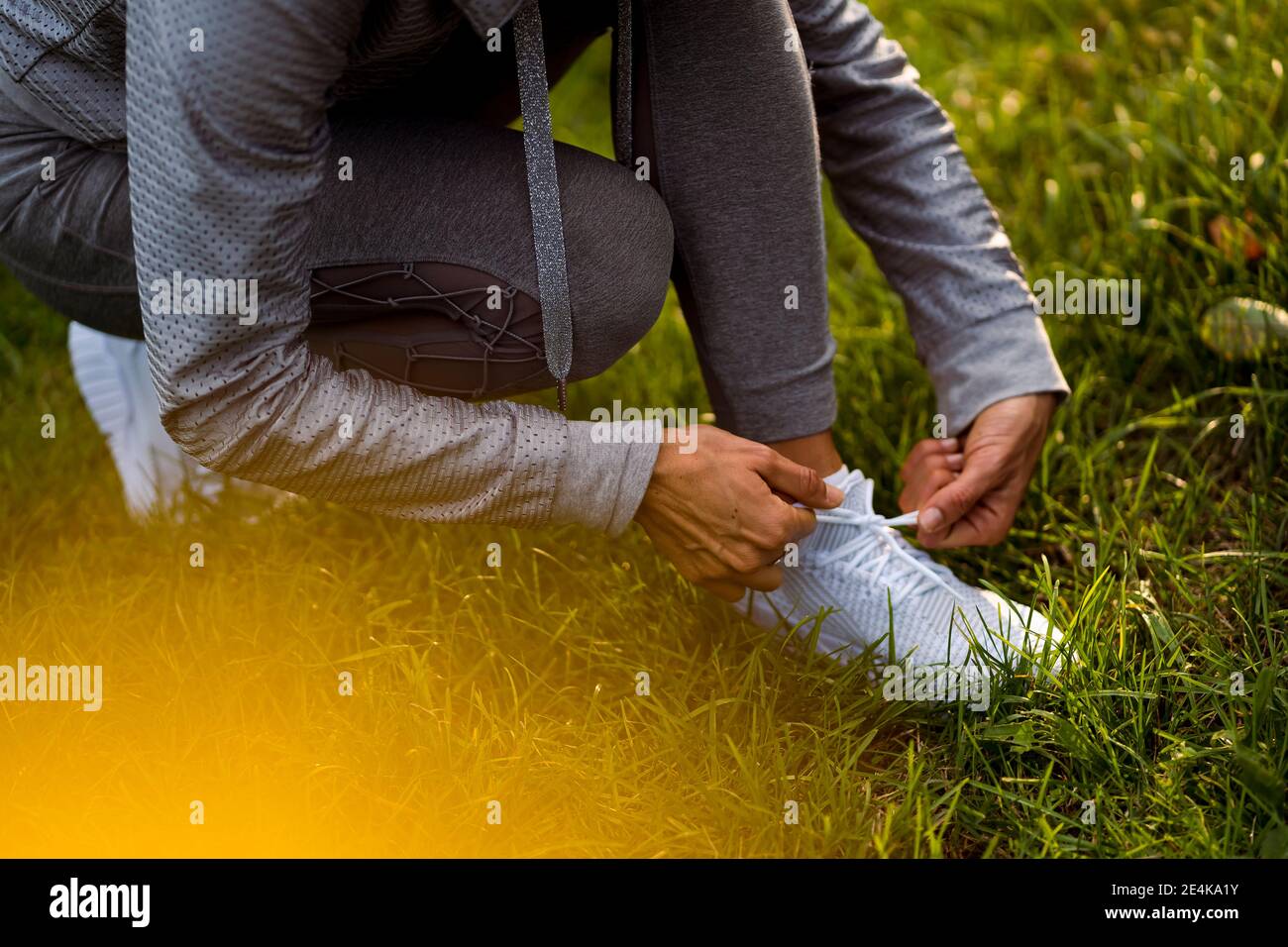 Sportswoman tying shoelace while crouching at park Stock Photo