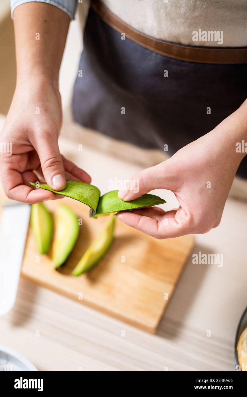 Hands of woman peeling avocados Stock Photo