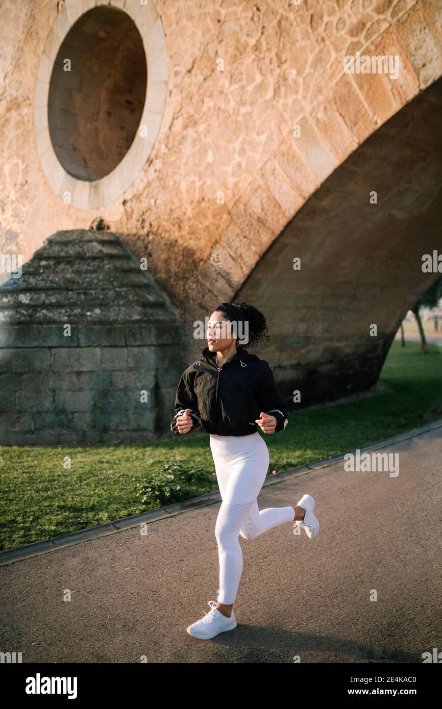 Sportswoman jogging on footpath in public park Stock Photo