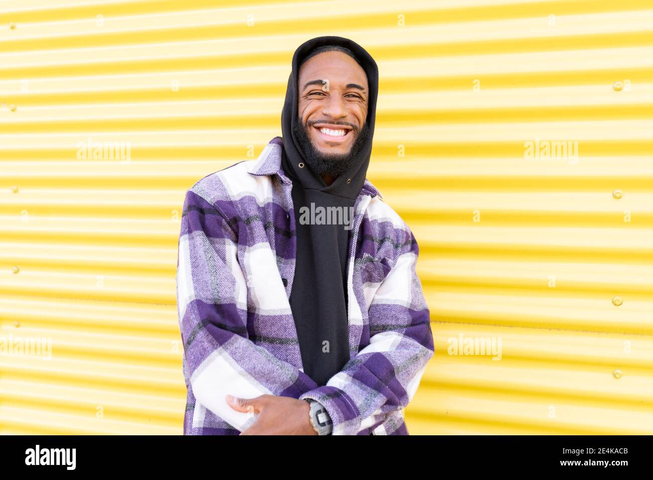 Smiling male rapper standing against yellow corrugated wall Stock Photo