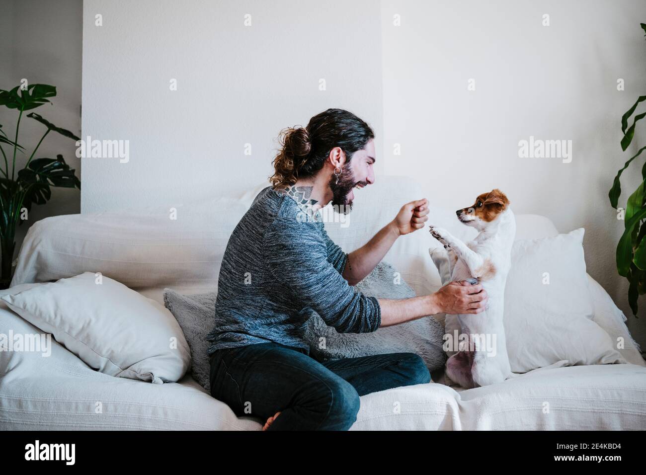 Happy man having fun while playing with dog at home Stock Photo