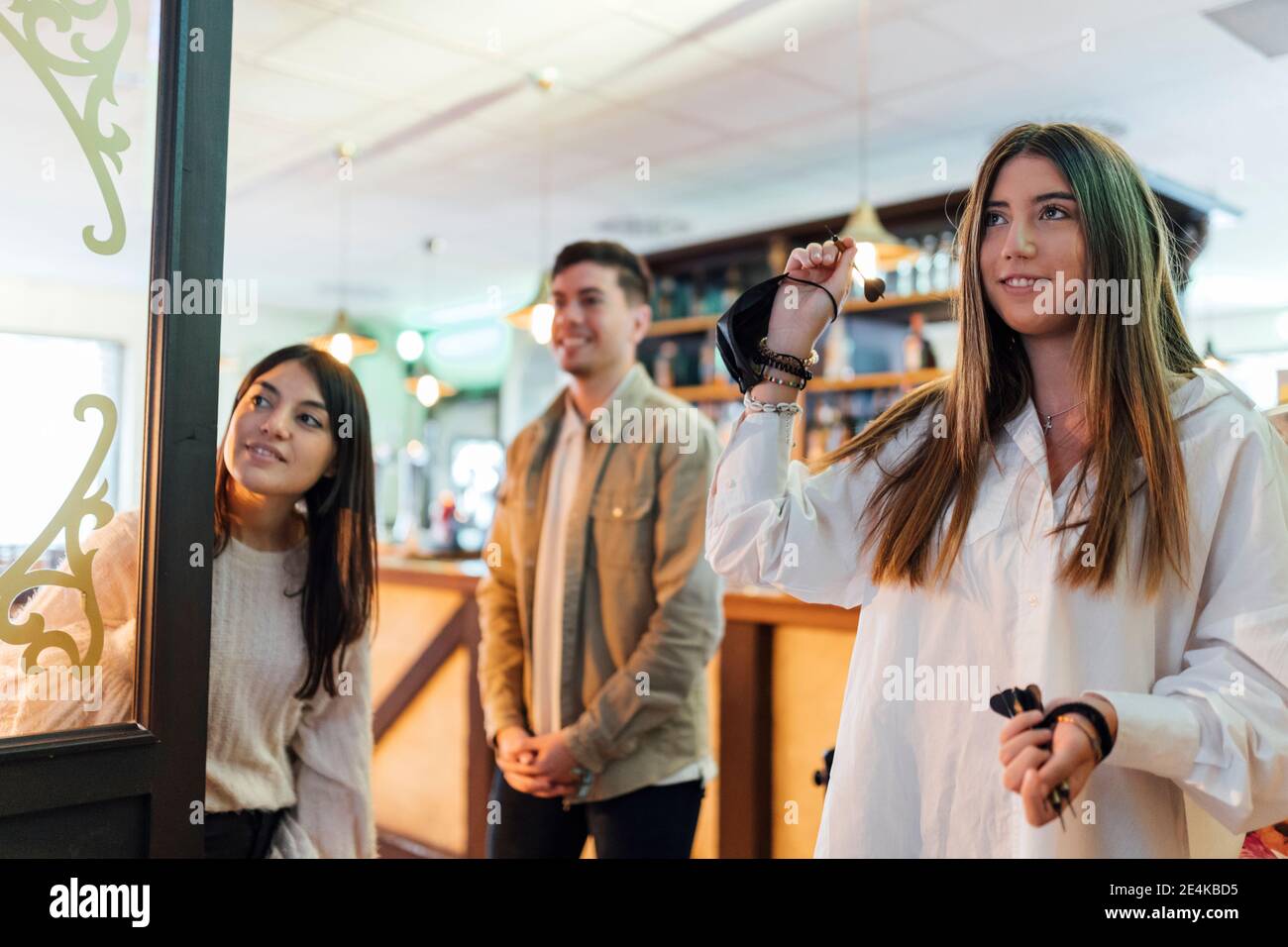 Teenager girl playing darts with friends in bar Stock Photo Alamy