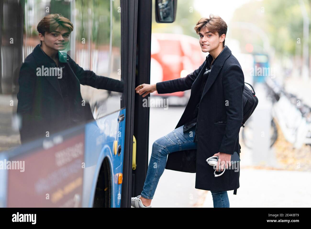 Handsome young man with backpack boarding bus in city Stock Photo