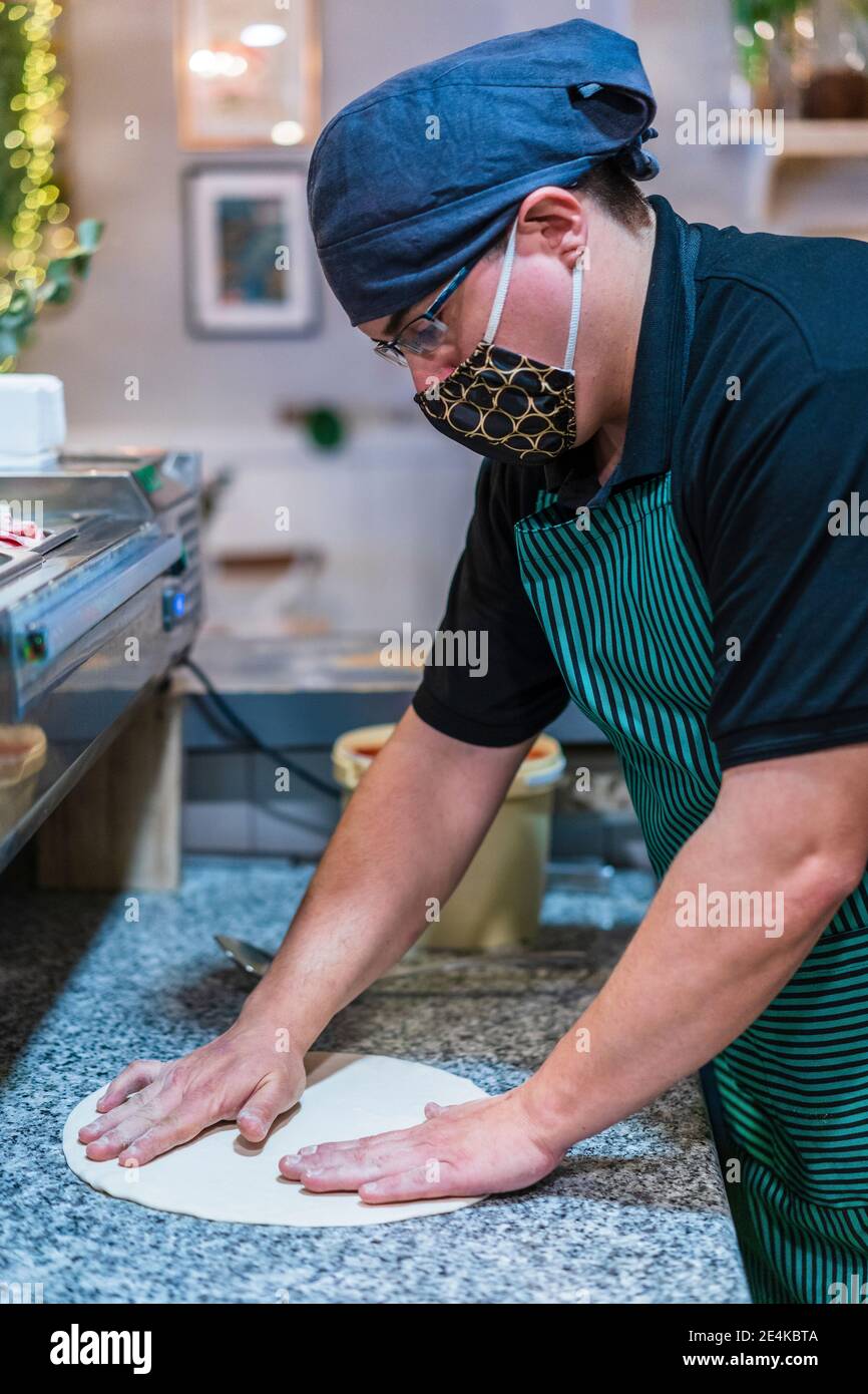 Male chef wearing protective face mask preparing pizza dough Stock Photo
