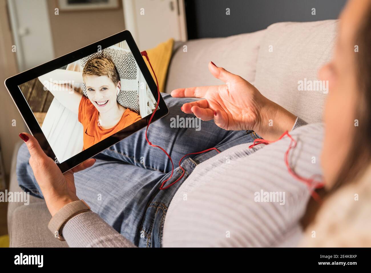 Mature woman gesturing while making video call to friend in living room Stock Photo
