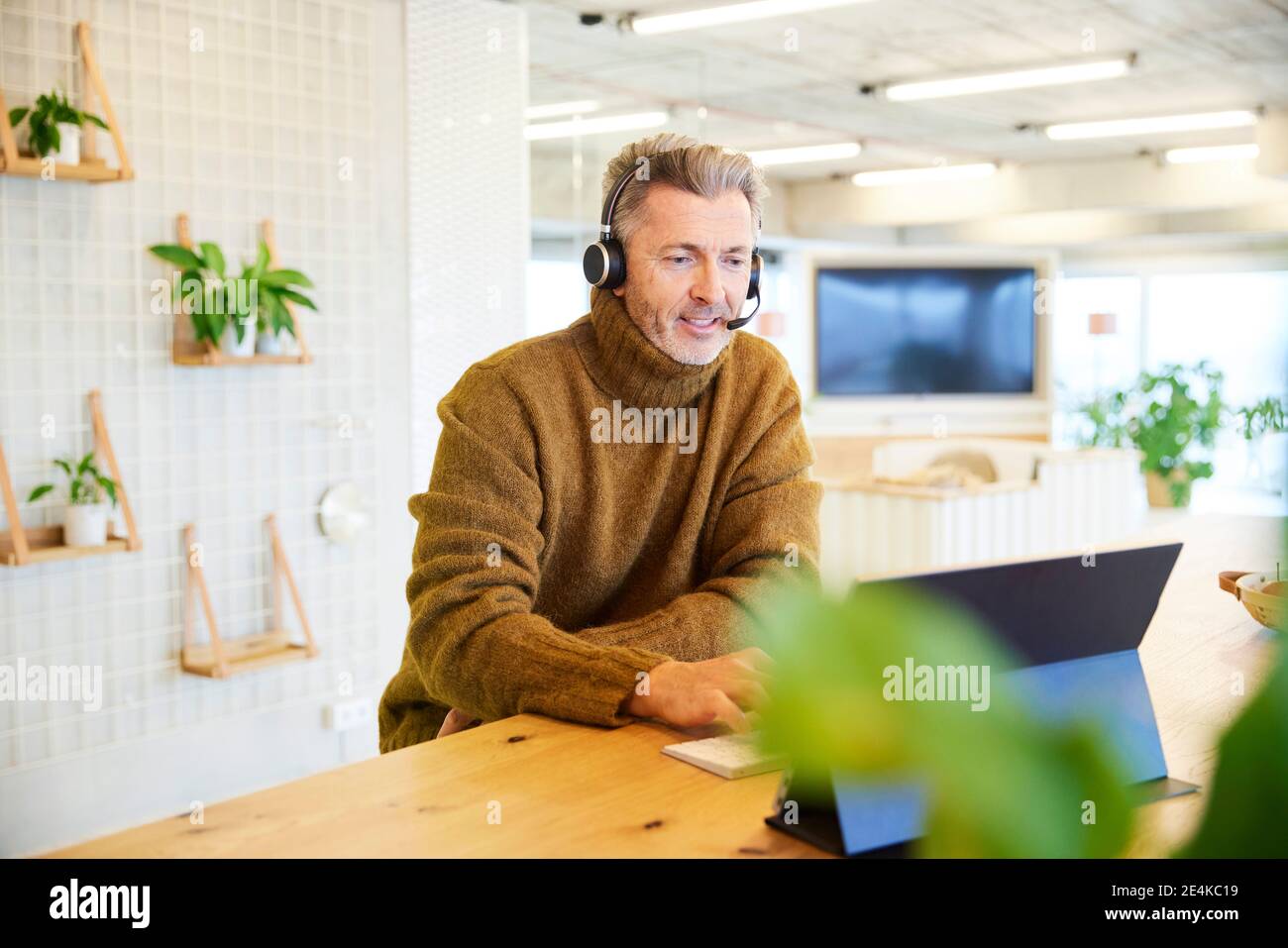 Businessman with headset talking while using digital tablet at office Stock Photo