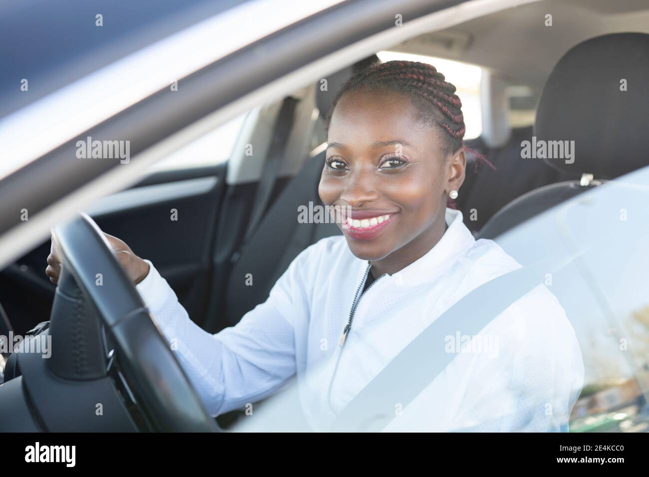 Smiling woman holding steering wheel while sitting in car Stock Photo