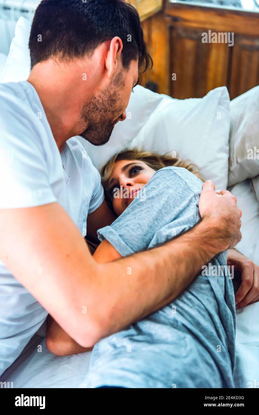 Happy affectionate young couple cuddling in bed at home Stock Photo