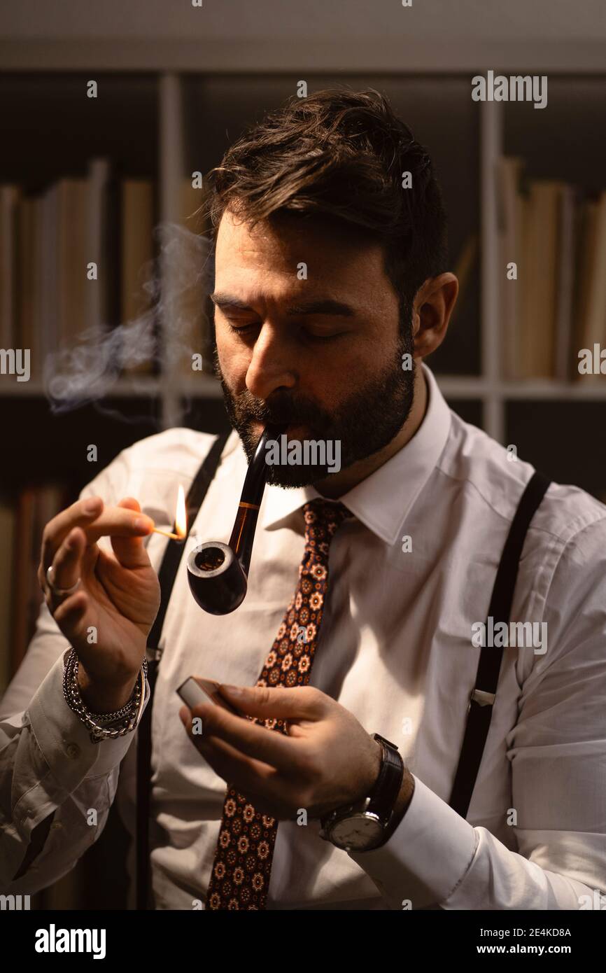 Portrait of bearded man lighting smoking pipe with match Stock Photo
