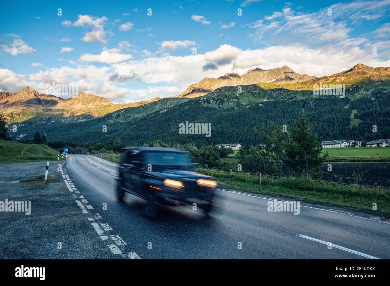Off-Road car driving along asphalt road in Engadin valley Stock Photo