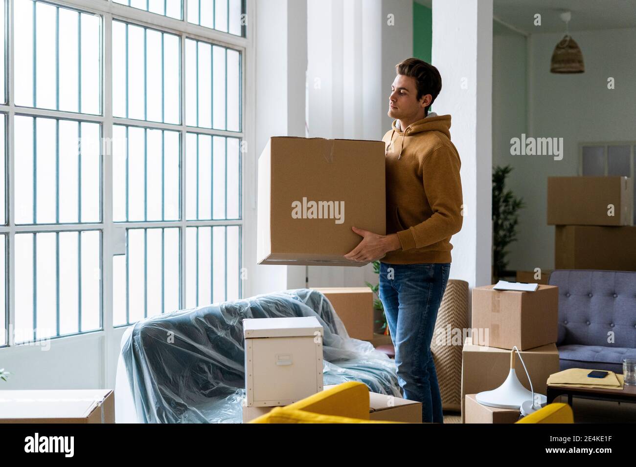 Young man carrying box while moving into new home Stock Photo Alamy