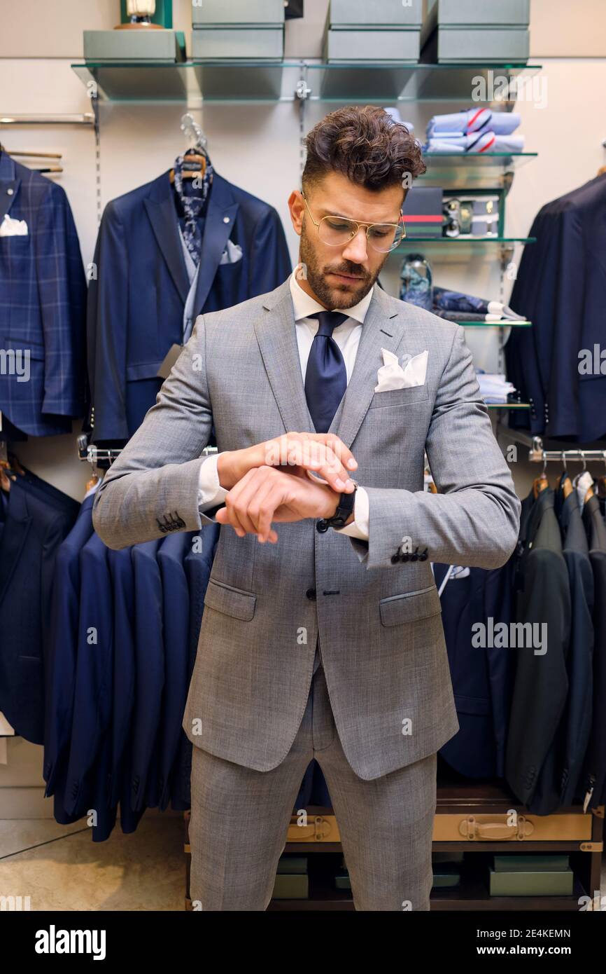 Man in gray suit checking time in tailors boutique Stock Photo