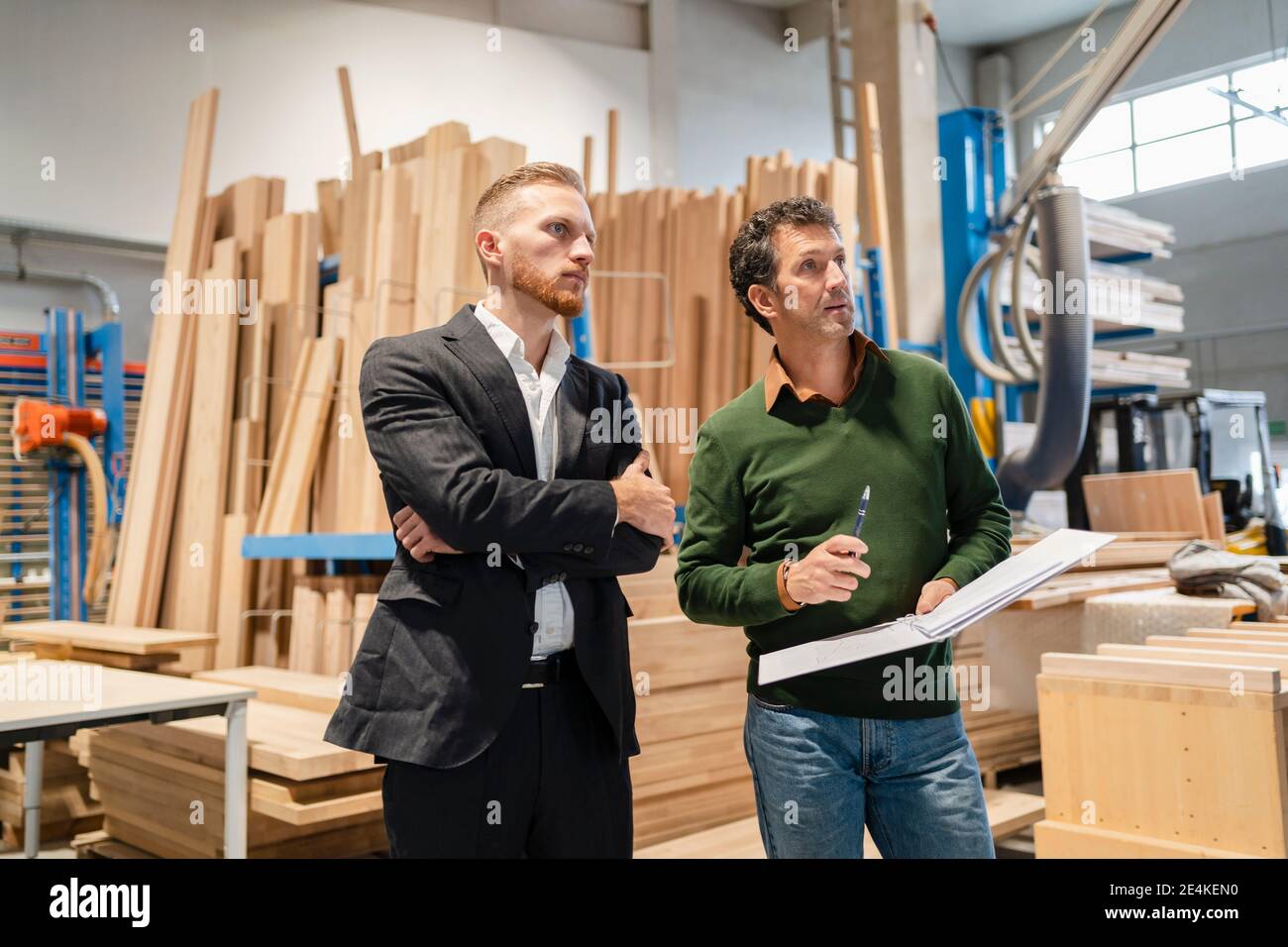 Two carpenters standing side by side and talking in production hall Stock Photo