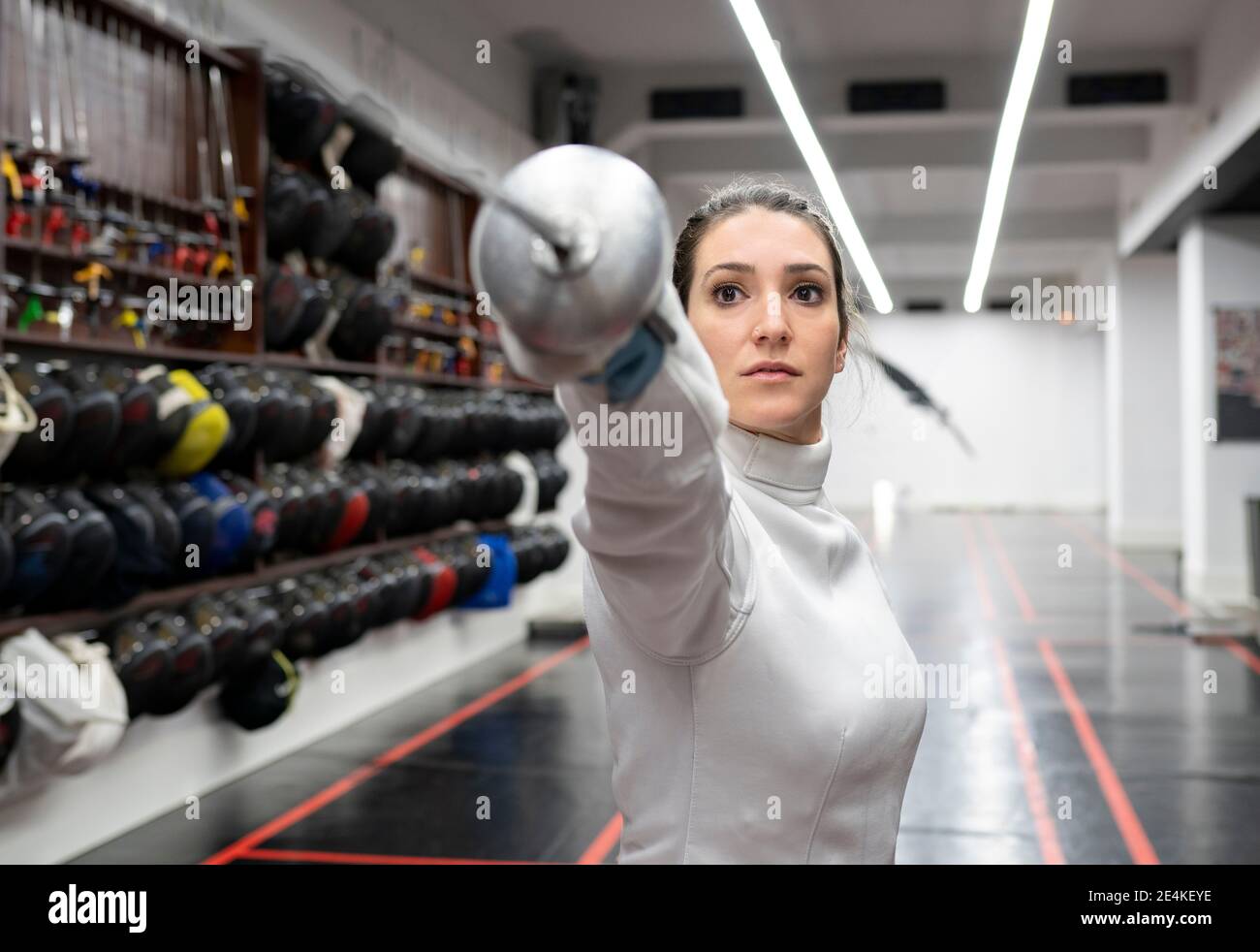 Woman in fencing outfit practicing at gym Stock Photo