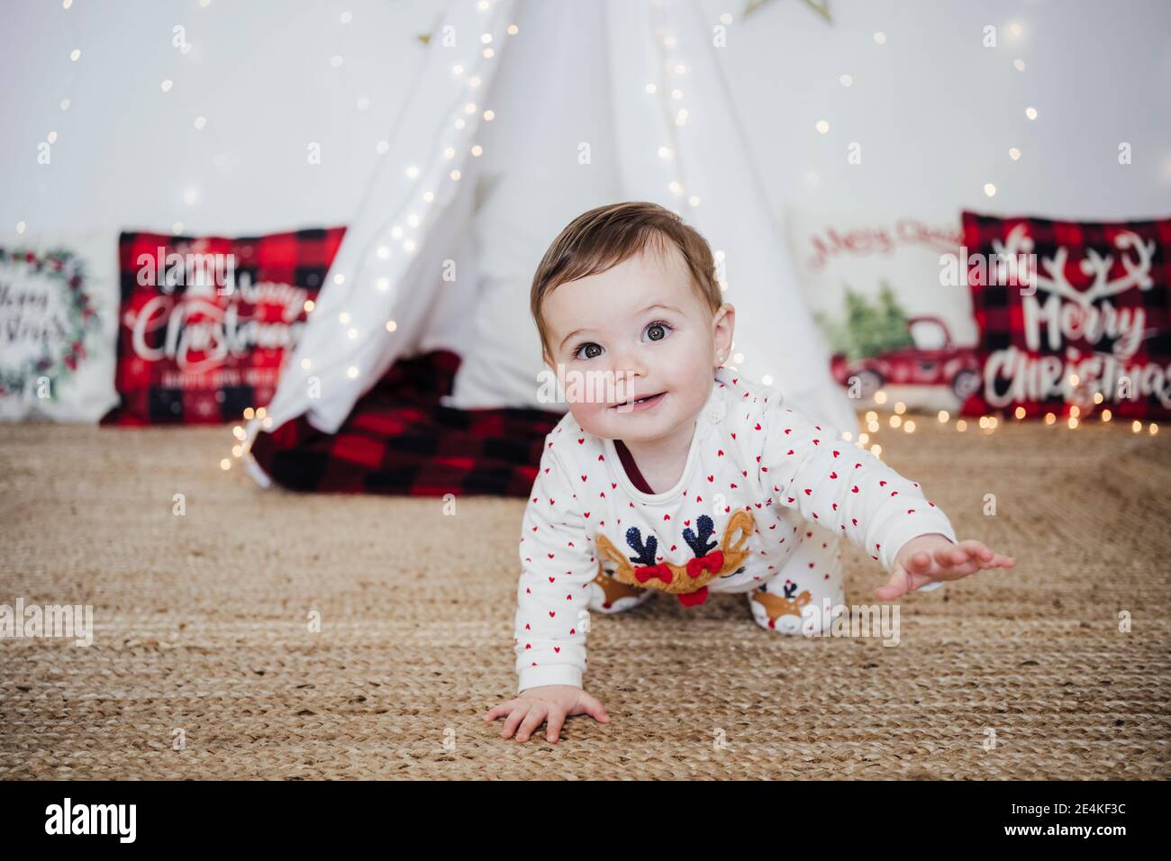 Cute baby girl smiling while crawling at home during Christmas Stock Photo